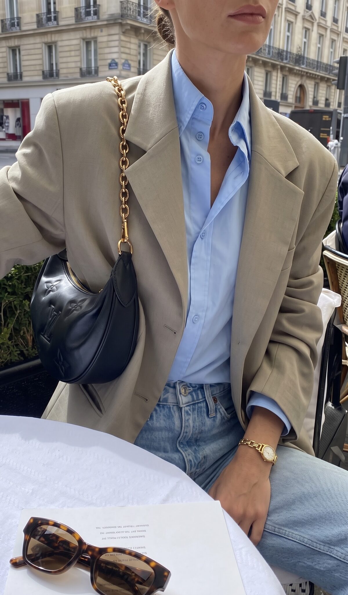 Beige tailored jacket over a light blue shirt with light wash jeans