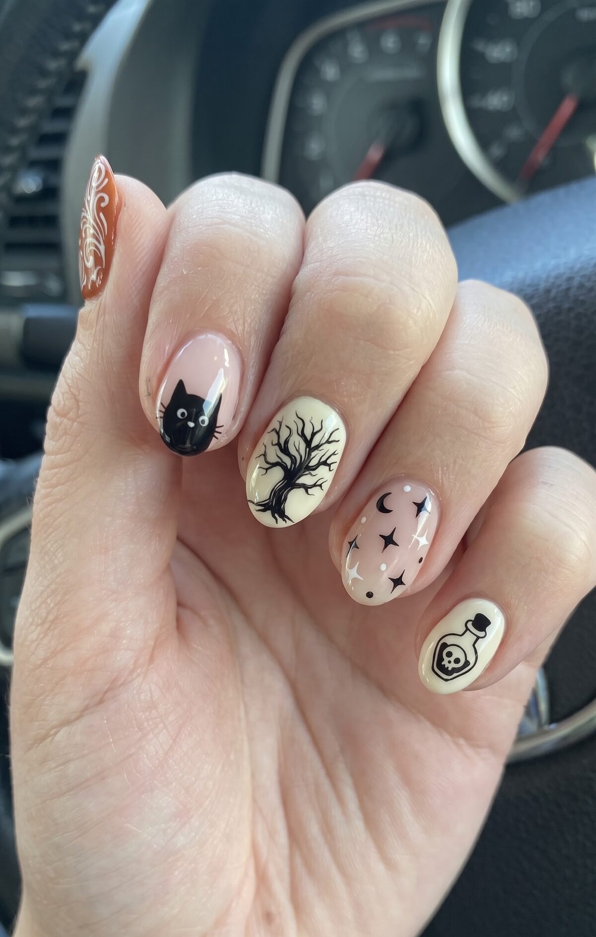 Nails with a black cat, bare spooky tree, moon and stars, and a poison bottle design