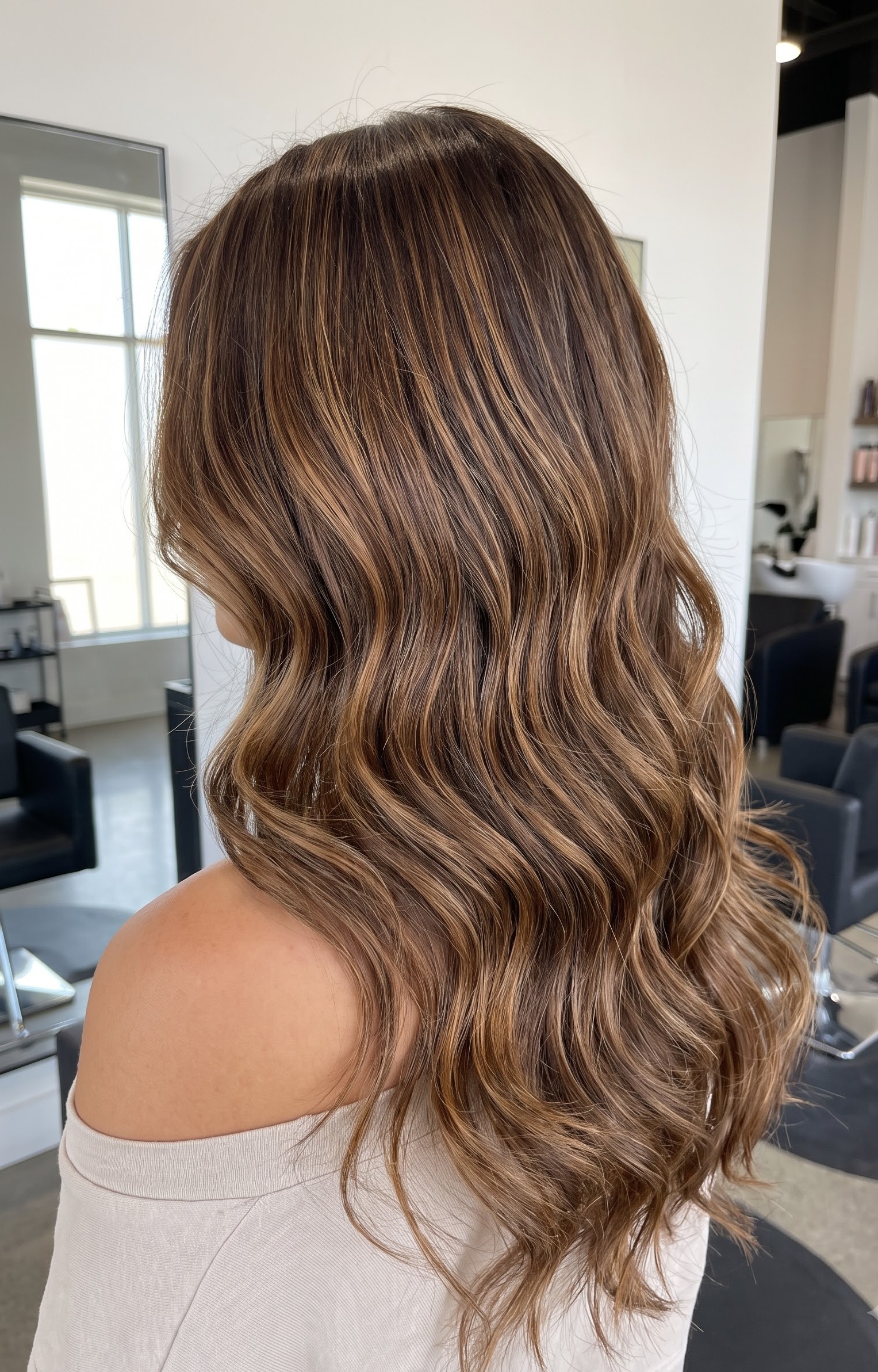 Brunette hair with soft caramel balayage highlights framing the face, styled in loose waves