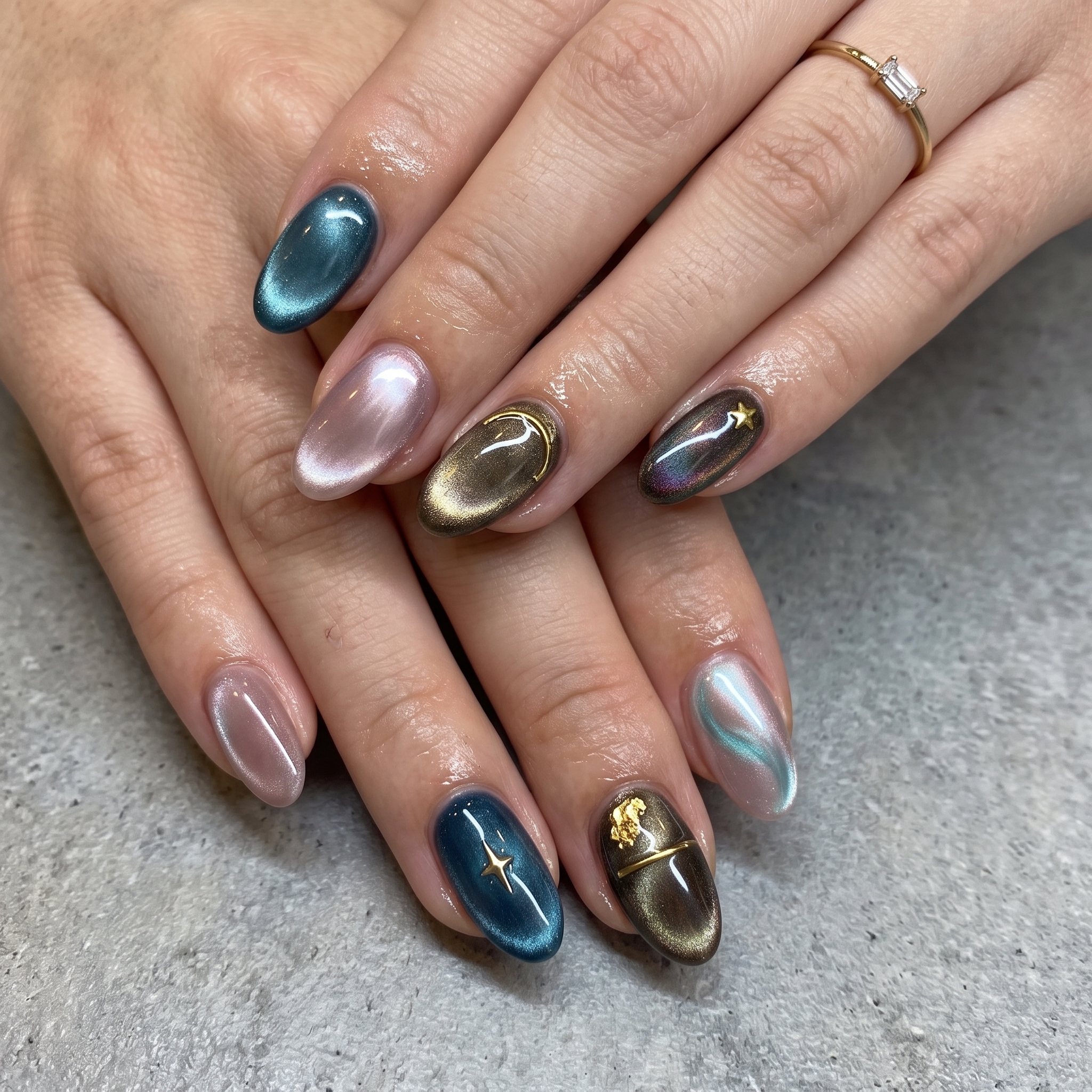 Celestial cat eye nails with blue, gold, and dark tones plus star charms