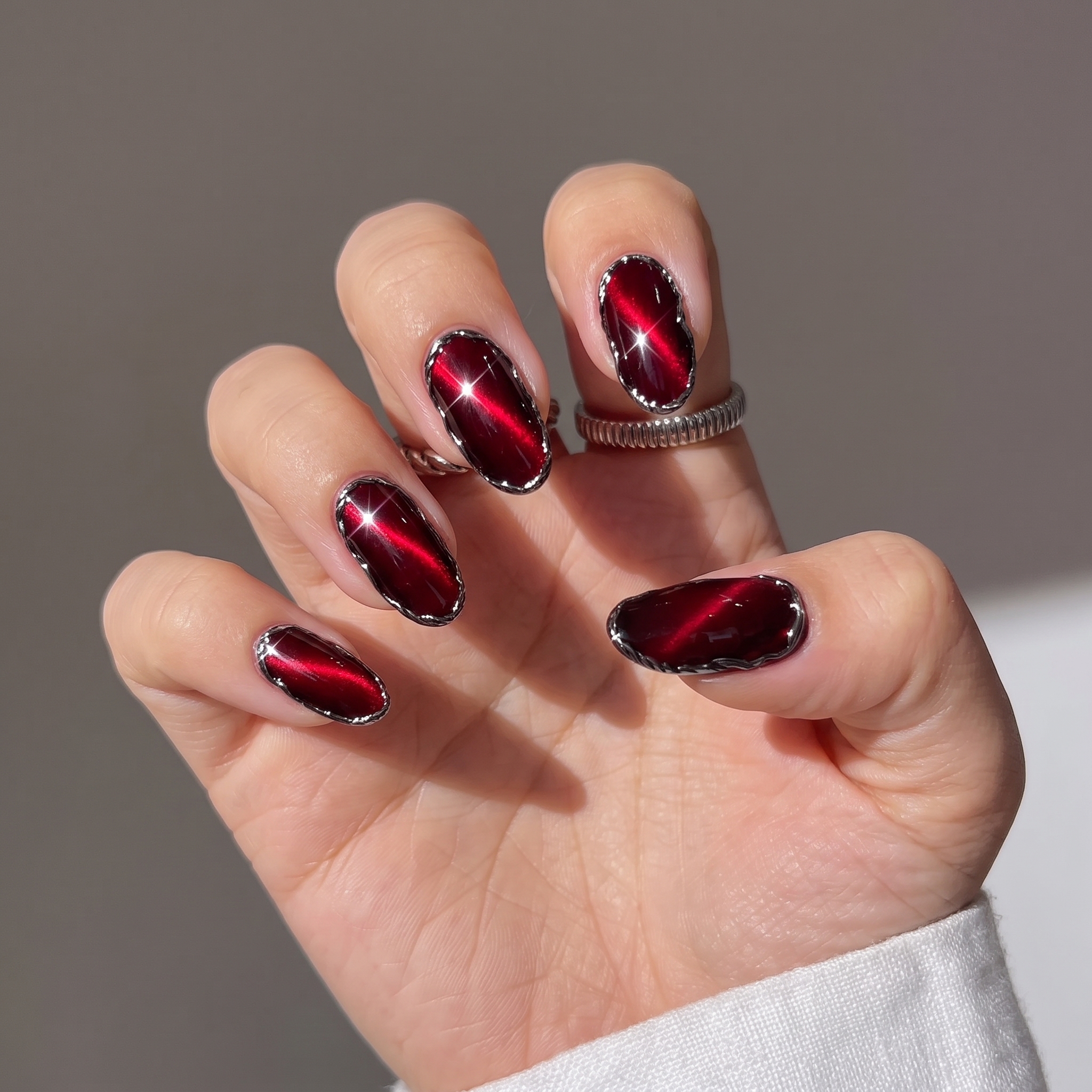 Ruby red cat eye nails outlined with silver chrome edging