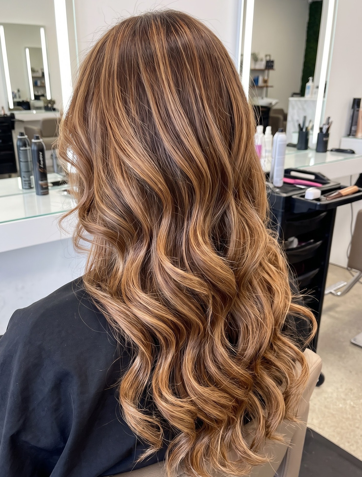 Brunette hair with rich copper balayage highlights through loose curled waves