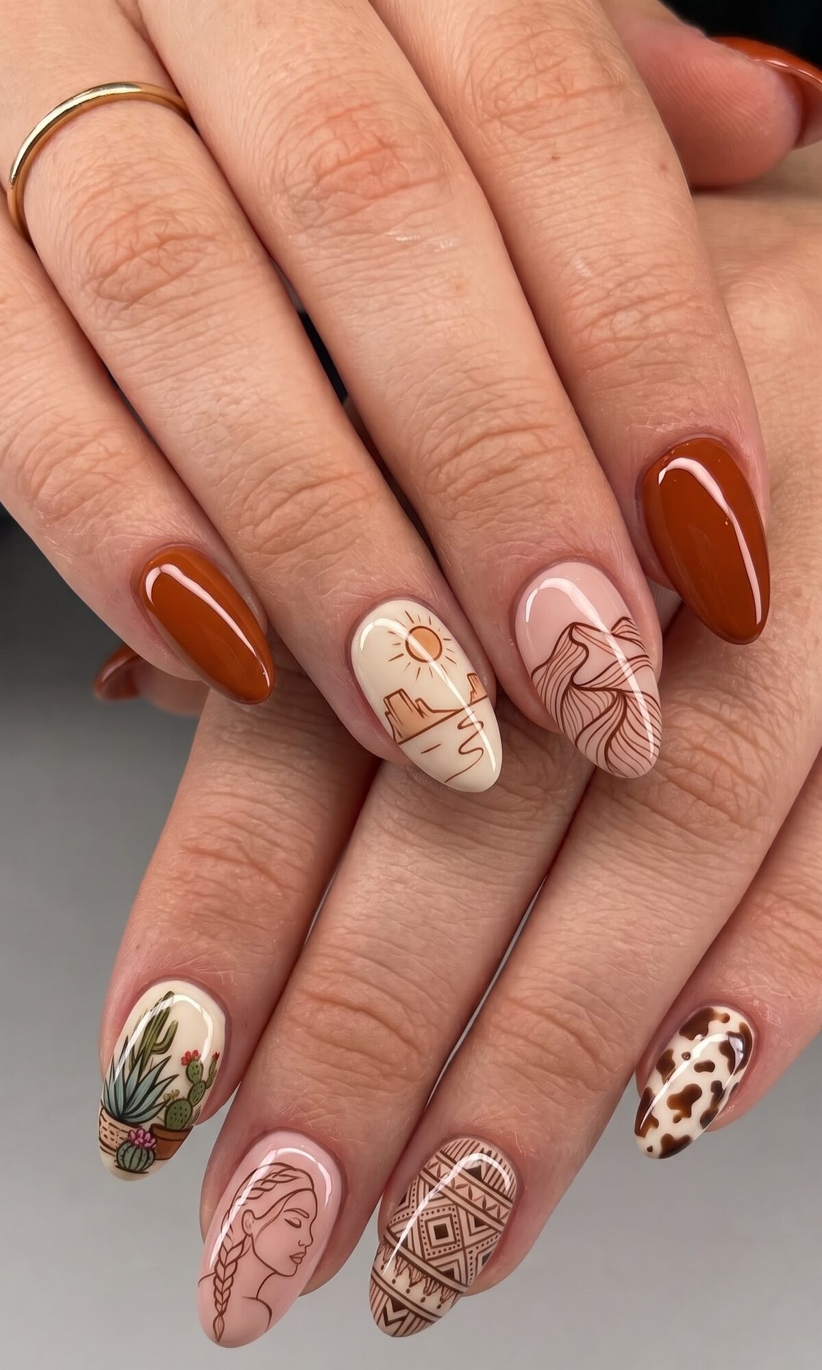 Burnt orange nails with desert scene line art, cactus, a woman's silhouette and Aztec pattern