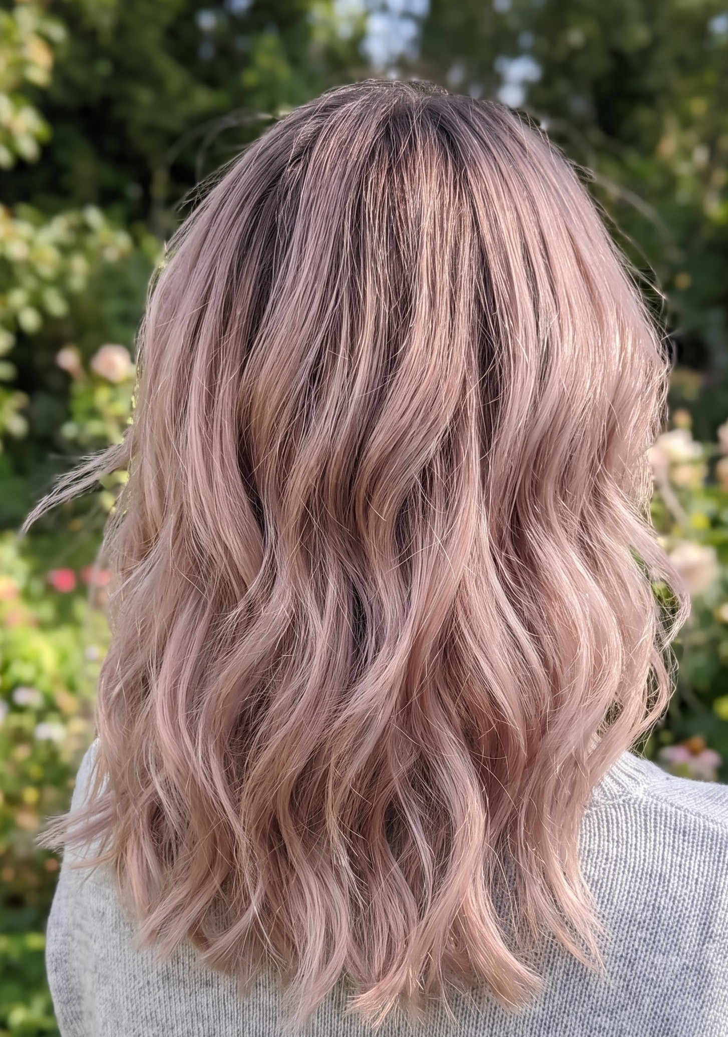 Dusty rose pastel pink hair color styled in soft waves outdoors