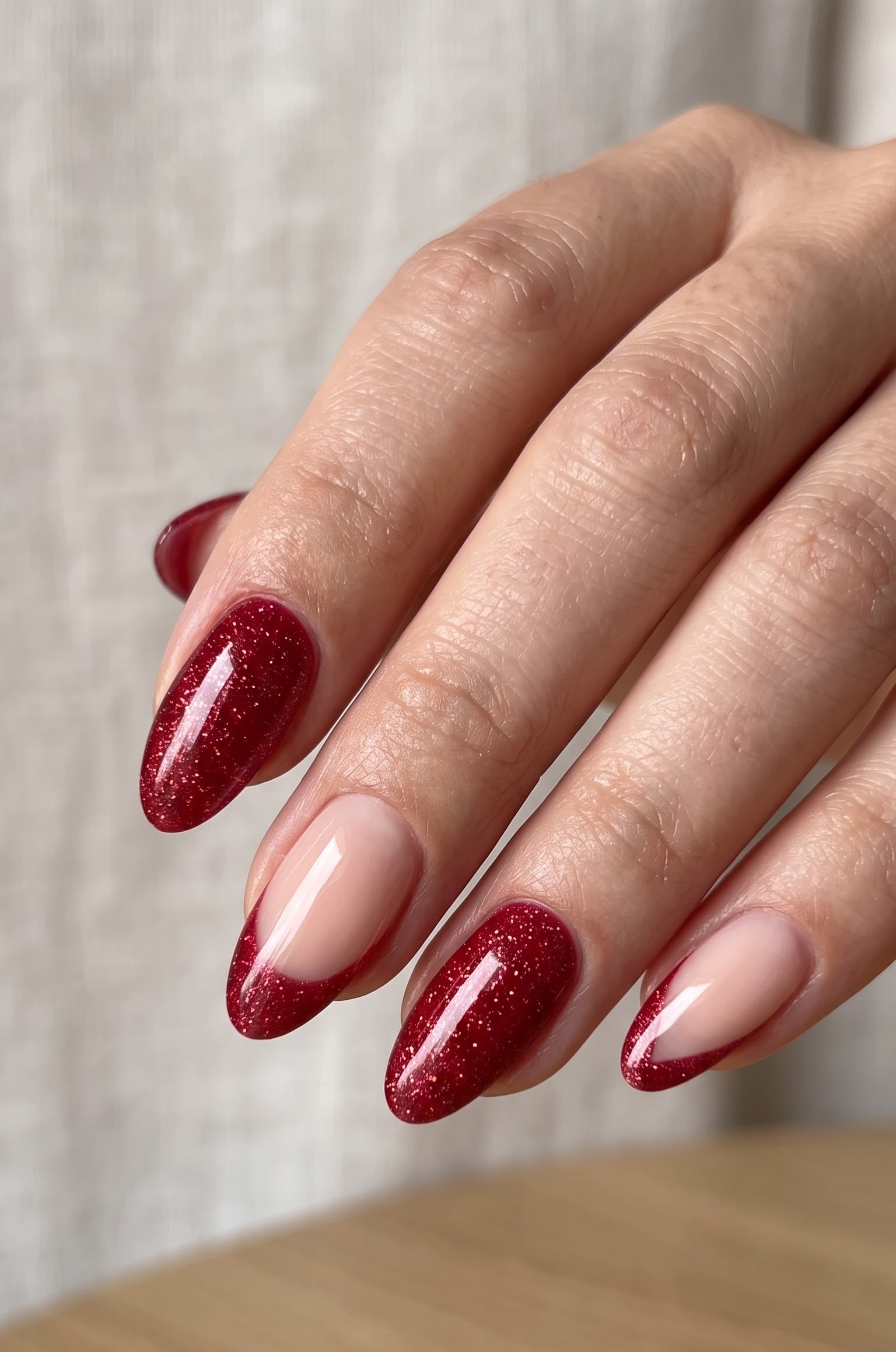 Nude almond nails with deep red glitter french tips