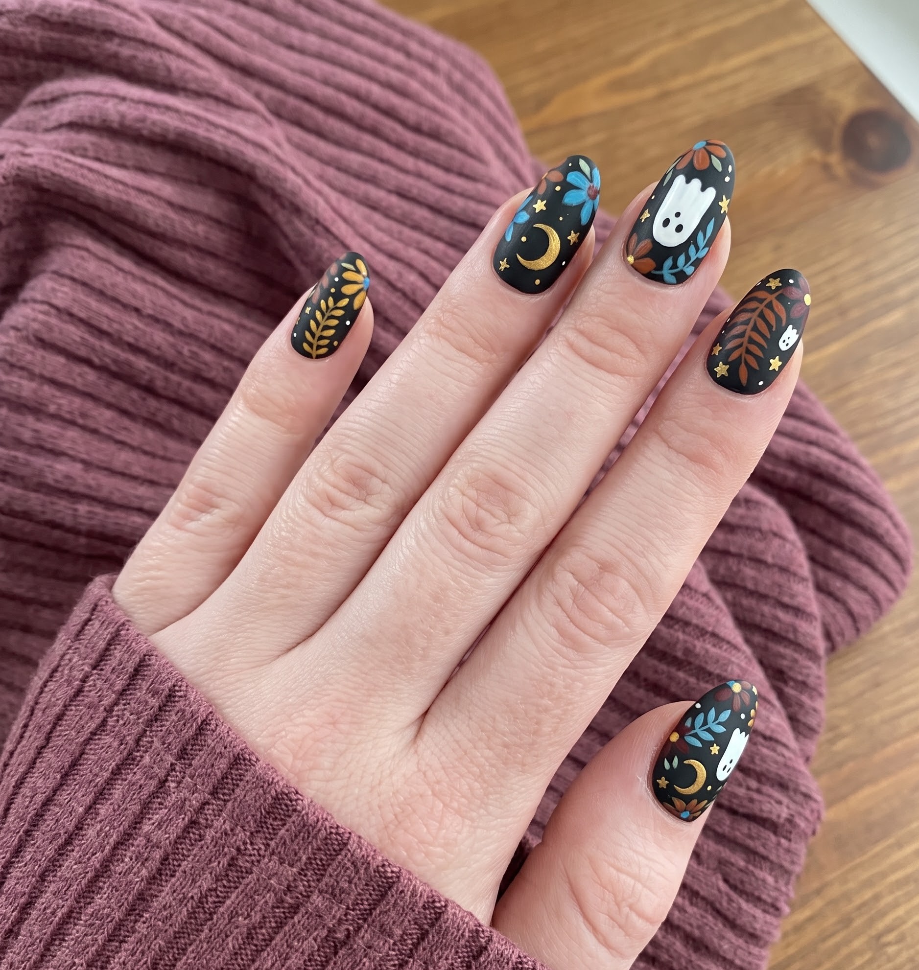 Matte black Halloween nails with gold and blue floral cottagecore ghost design