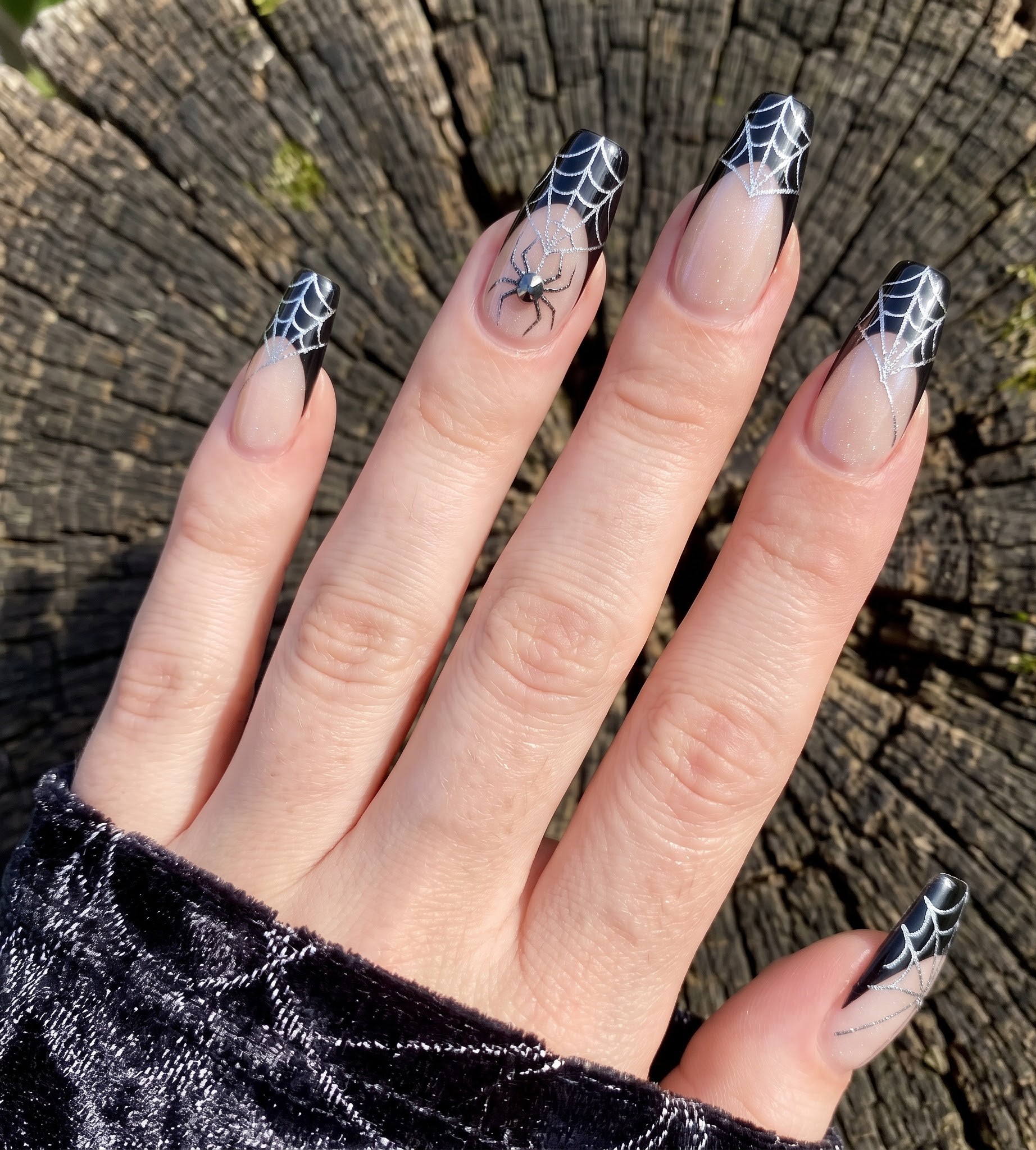 Glossy black french tip Halloween nails with a silver spiderweb and jeweled spider accent