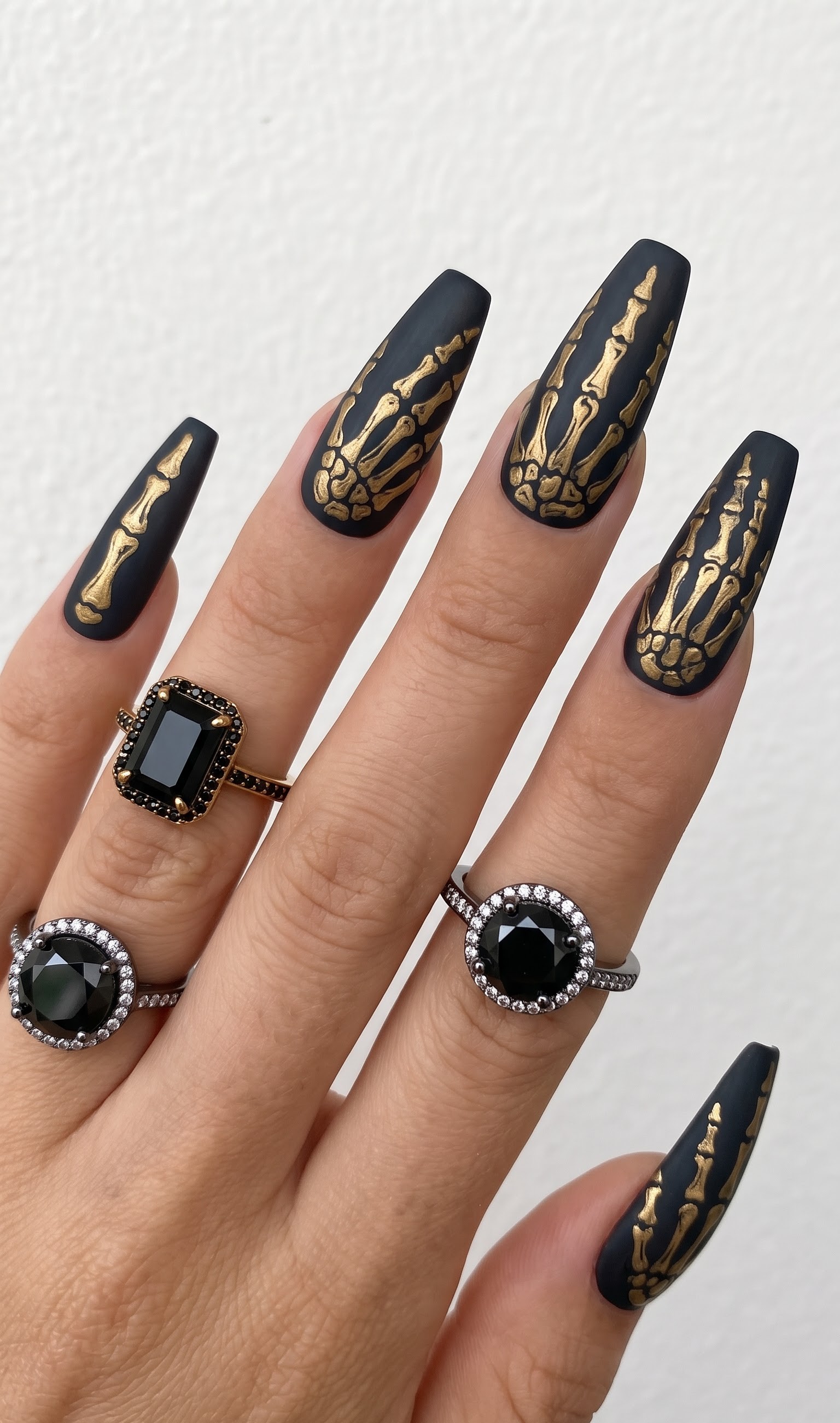 Matte black Halloween nails with gold skeleton hand bones