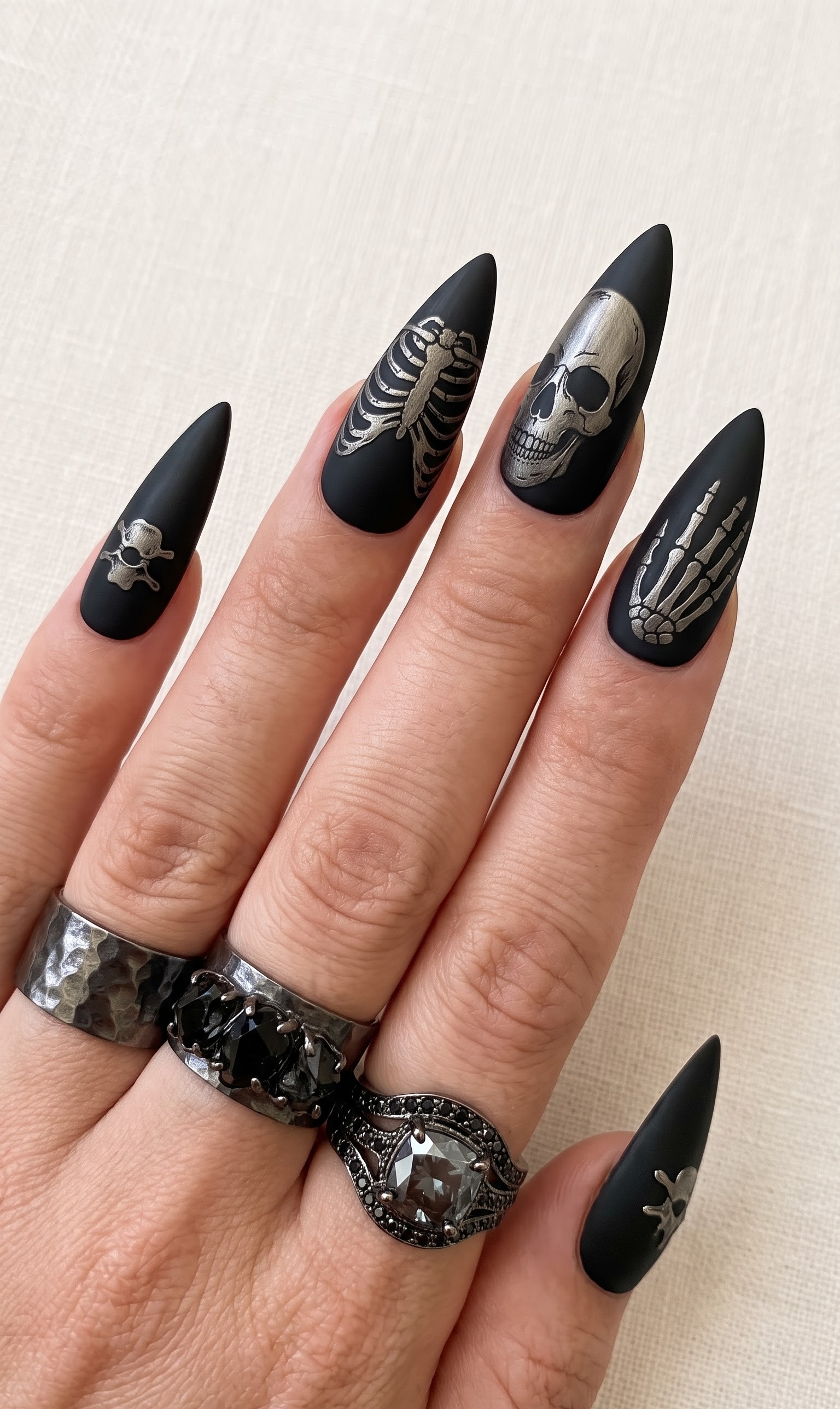Matte black stiletto Halloween nails with silver skull ribcage and skeleton hand