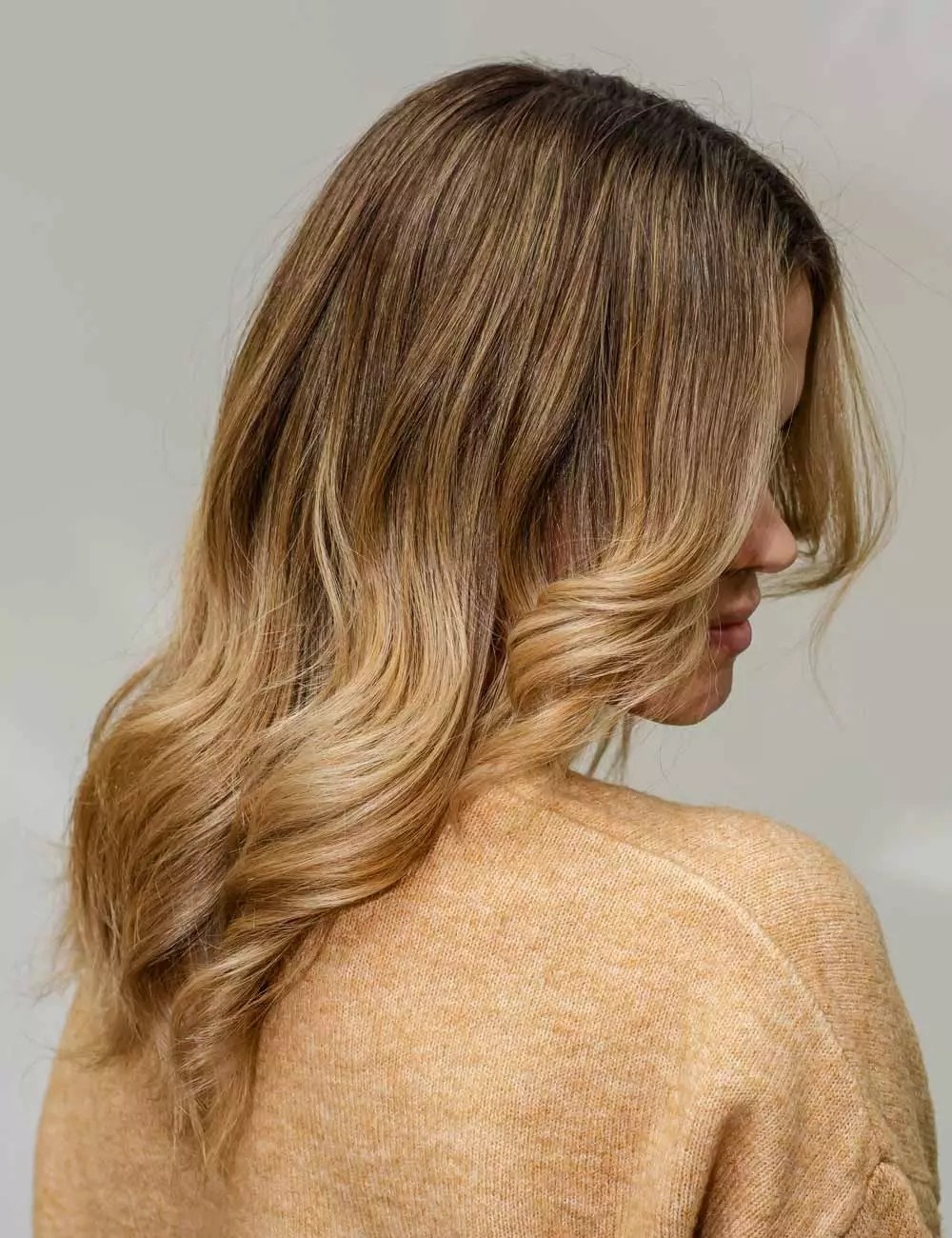 Honey blonde hair with dimensional balayage styled in side-swept waves