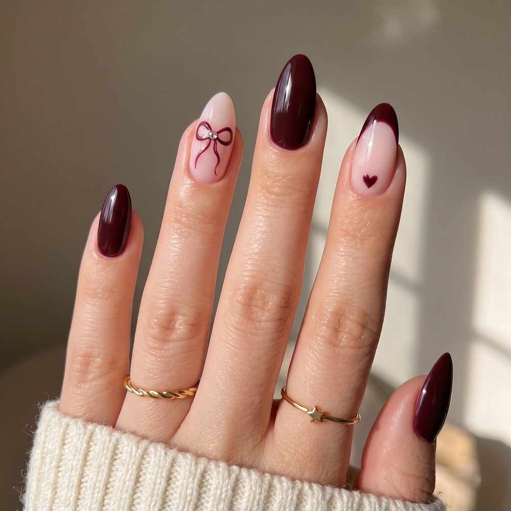 Burgundy almond nails with a hand-painted bow and heart accent nail