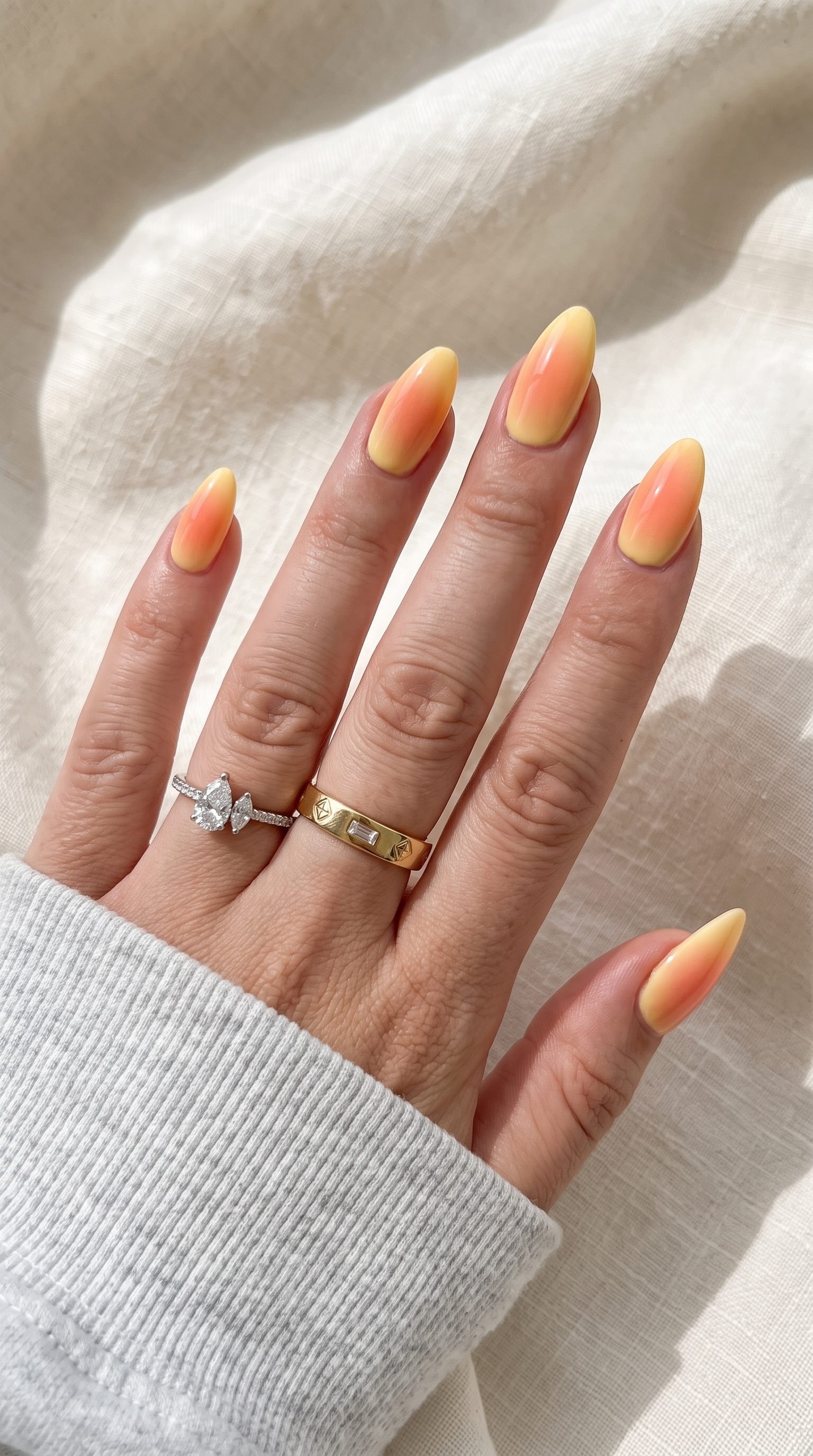 Peach orange ombre summer nails with gold and silver rings almond shape