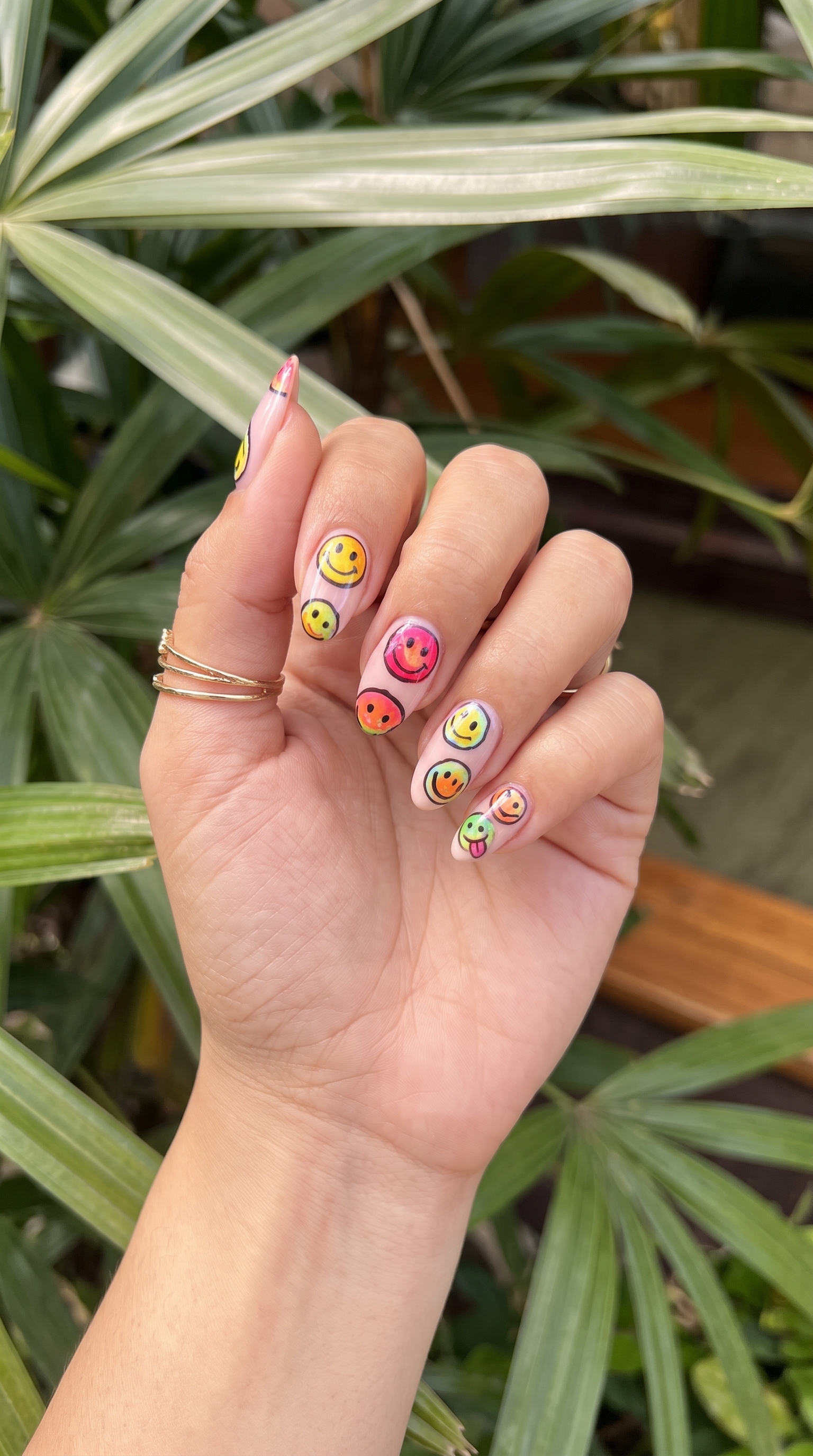 Smiley face summer nails with multicoloured happy faces on sheer pink base almond